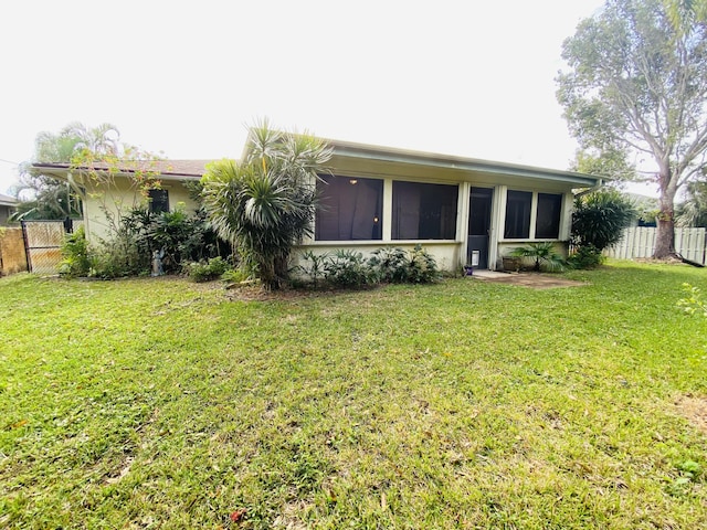 back of house with a lawn and a sunroom