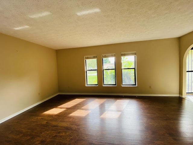 empty room with a textured ceiling and dark wood-type flooring