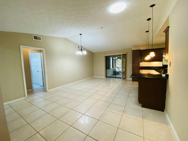 kitchen with a textured ceiling, pendant lighting, light tile patterned floors, a chandelier, and lofted ceiling