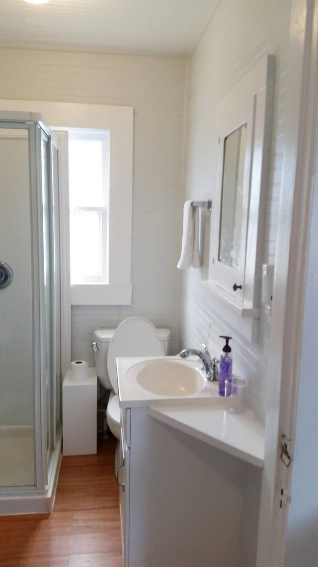 bathroom featuring vanity, hardwood / wood-style floors, toilet, and a shower with door