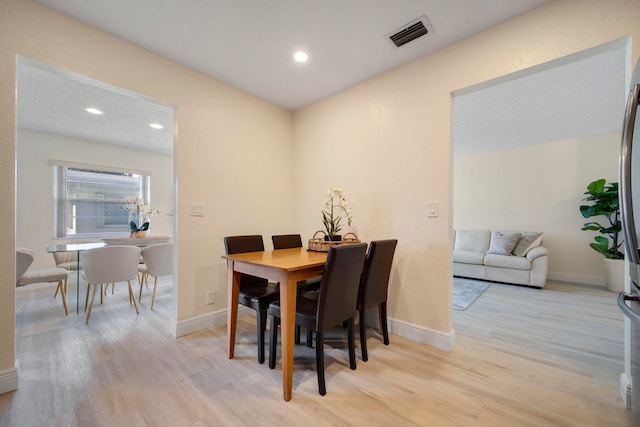 dining room with a textured ceiling and light wood-type flooring