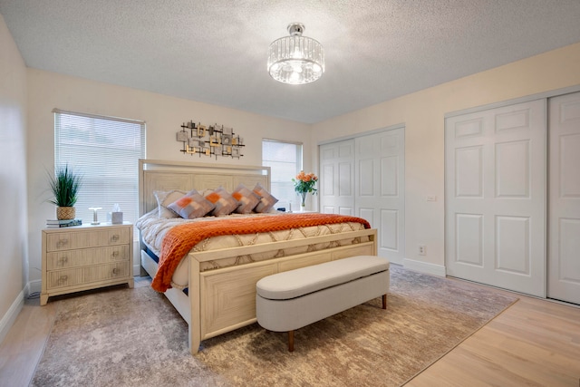 bedroom featuring hardwood / wood-style floors, a notable chandelier, multiple windows, and a textured ceiling