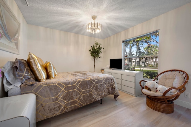 bedroom featuring light hardwood / wood-style flooring, a textured ceiling, and a chandelier