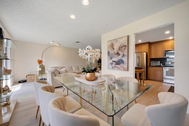 dining space featuring light hardwood / wood-style flooring and a textured ceiling