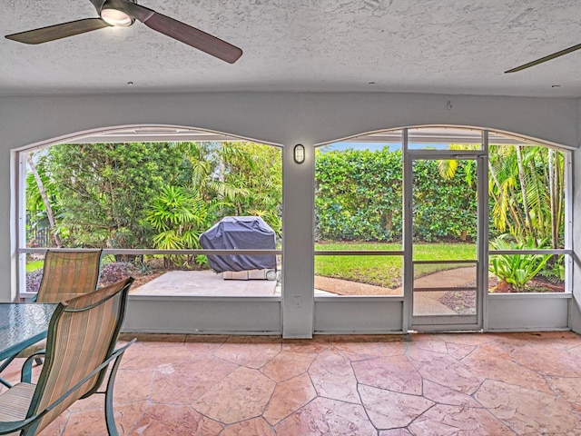 unfurnished sunroom featuring ceiling fan and a wealth of natural light