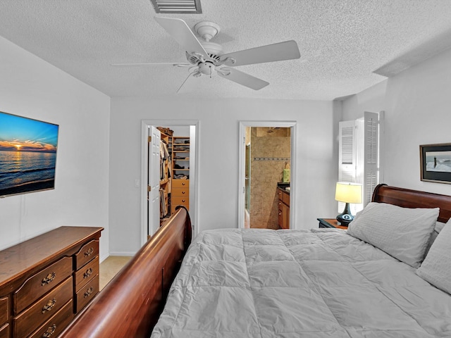 bedroom featuring ensuite bathroom, a spacious closet, a textured ceiling, a closet, and ceiling fan