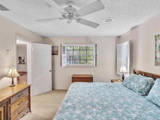 bedroom featuring ceiling fan, a textured ceiling, and light colored carpet