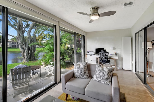 sunroom / solarium featuring a water view and ceiling fan