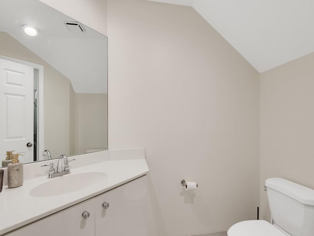 bathroom featuring toilet, vanity, and vaulted ceiling