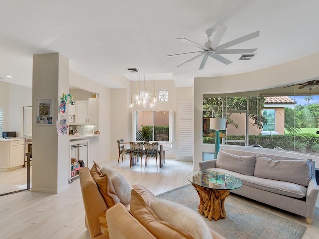 living room with light hardwood / wood-style floors and ceiling fan with notable chandelier