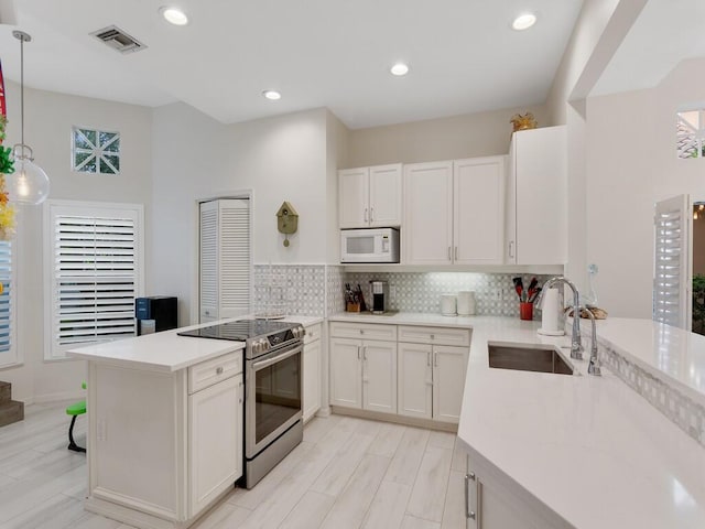 kitchen with white cabinetry, stainless steel range with electric stovetop, sink, and hanging light fixtures