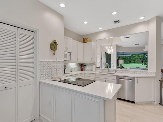 kitchen featuring kitchen peninsula, hanging light fixtures, white cabinetry, dishwasher, and sink