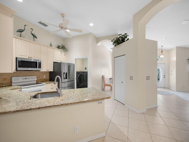 kitchen featuring independent washer and dryer, kitchen peninsula, appliances with stainless steel finishes, and light stone counters