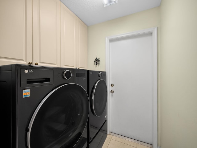 laundry area featuring cabinets, independent washer and dryer, a textured ceiling, and light tile patterned floors