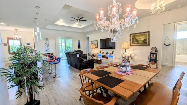 dining room with ornamental molding, a tray ceiling, light wood-type flooring, and ceiling fan