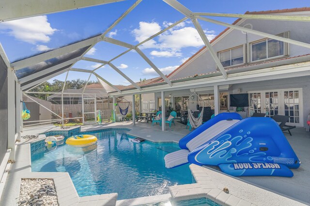 view of patio with a lanai, ceiling fan, a fenced in pool, and a storage shed