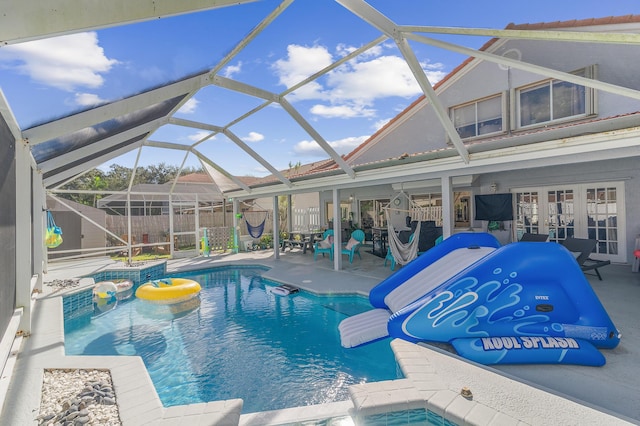 view of swimming pool featuring an in ground hot tub, a lanai, a water slide, and a patio area