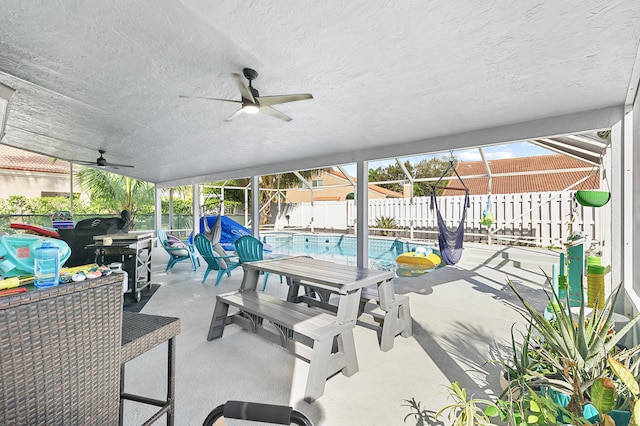 view of patio with ceiling fan, a fenced in pool, glass enclosure, and area for grilling