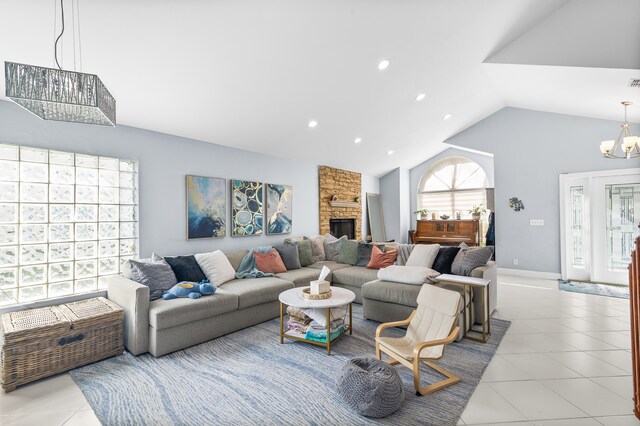 tiled living room with lofted ceiling, a fireplace, and an inviting chandelier