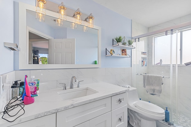 bathroom with toilet, a healthy amount of sunlight, tile walls, and vanity