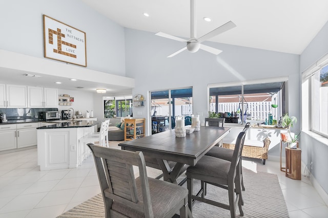 dining area featuring ceiling fan, light tile patterned floors, and high vaulted ceiling