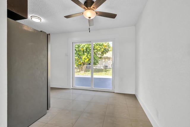 spare room with a textured ceiling, ceiling fan, and light tile patterned flooring