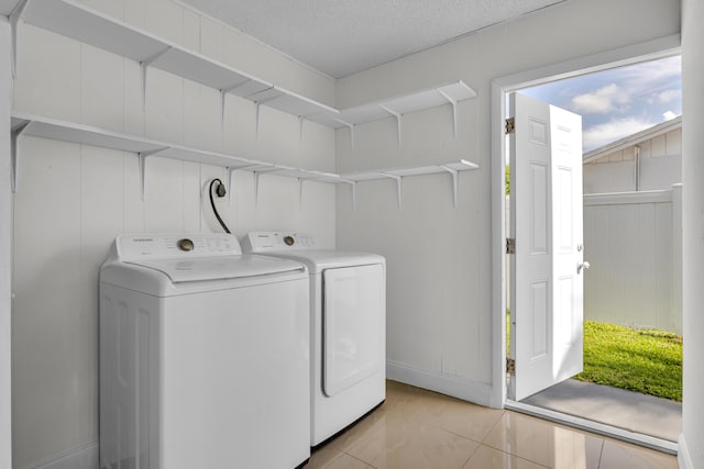 laundry room featuring washer and dryer, light tile patterned floors, and a textured ceiling