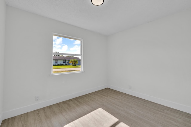 unfurnished room with light hardwood / wood-style flooring and a textured ceiling