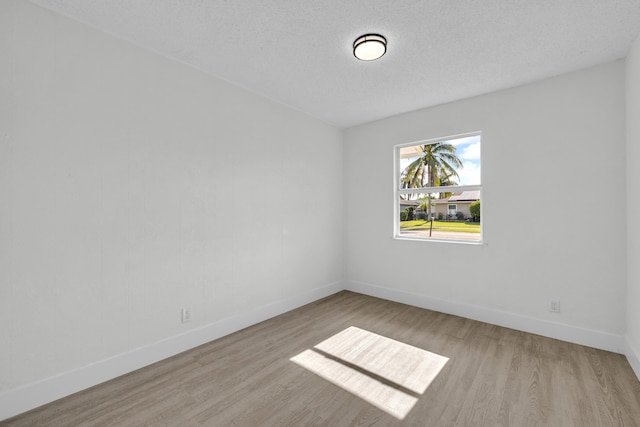 empty room with light hardwood / wood-style floors and a textured ceiling