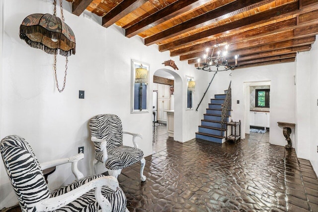 interior space featuring beamed ceiling, stairway, wooden ceiling, arched walkways, and a notable chandelier