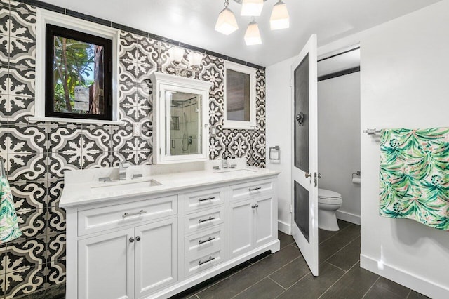 full bathroom with a sink, baseboards, toilet, and double vanity