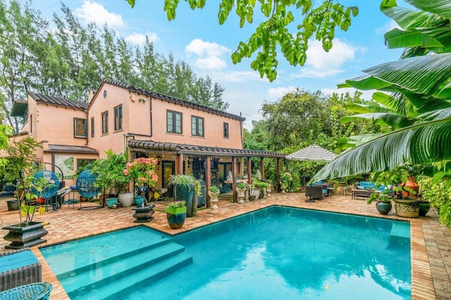 rear view of house featuring a pergola, an outdoor pool, a tile roof, and a patio