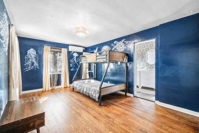 bedroom with a wall mounted air conditioner, baseboards, and wood finished floors