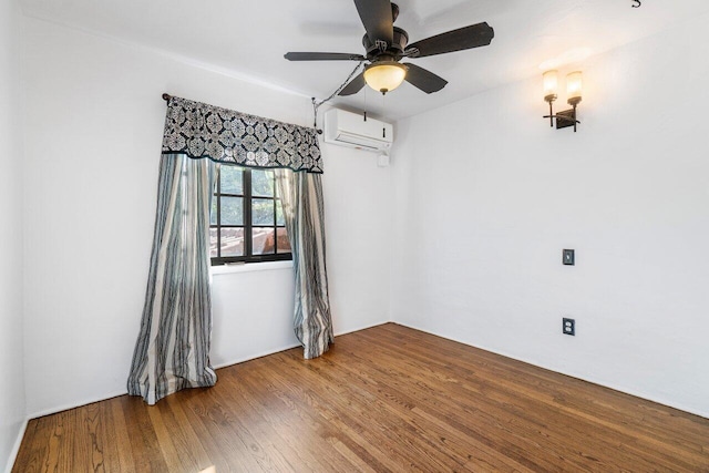 empty room featuring a wall mounted AC, a ceiling fan, and wood finished floors