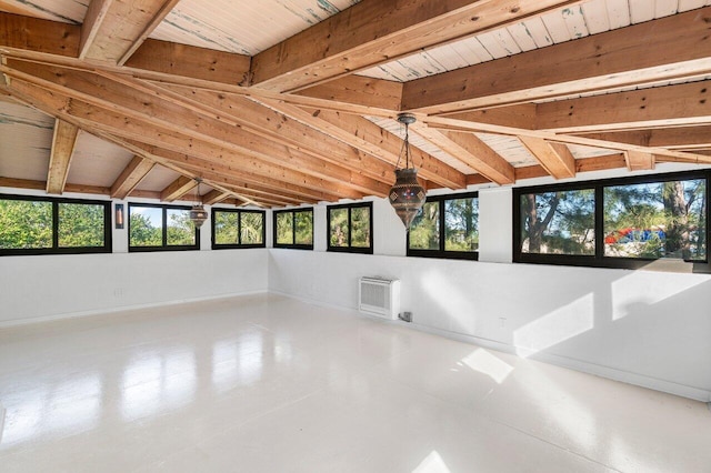 unfurnished room featuring heating unit and vaulted ceiling with beams