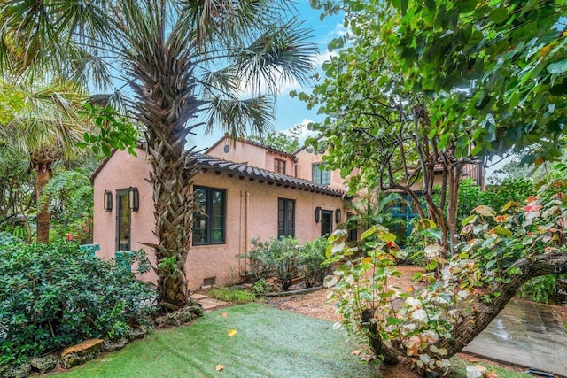 view of side of property featuring stucco siding, a tile roof, and crawl space