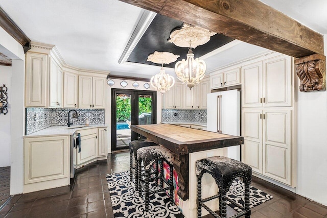 kitchen featuring butcher block countertops, a sink, stainless steel dishwasher, backsplash, and an inviting chandelier