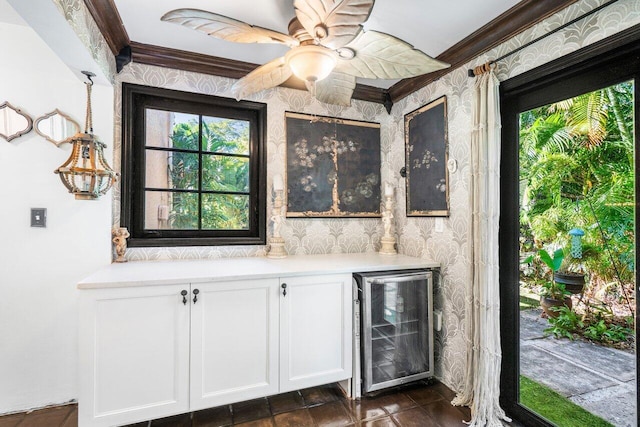 bar with wallpapered walls, a ceiling fan, beverage cooler, and ornamental molding