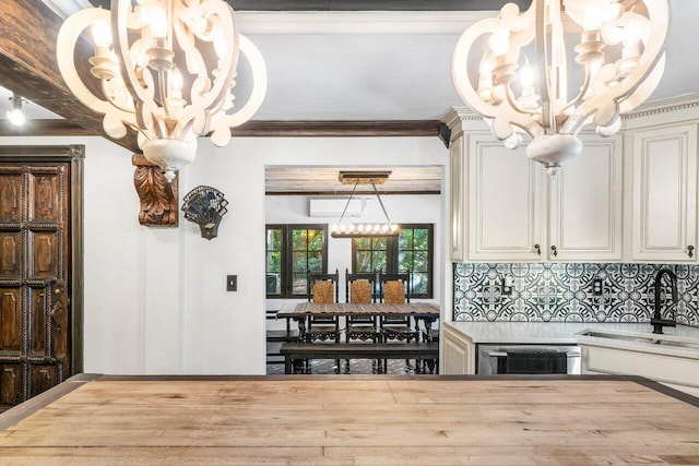 kitchen with crown molding, light countertops, decorative backsplash, an inviting chandelier, and cream cabinetry