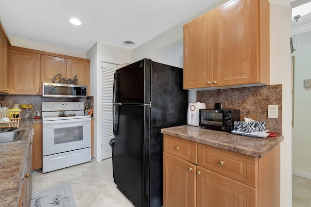 kitchen featuring tasteful backsplash, light stone countertops, light tile patterned flooring, black refrigerator, and electric stove