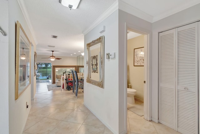 hallway featuring crown molding, a textured ceiling, and light tile patterned floors