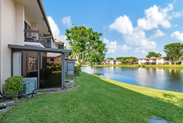 view of yard featuring a balcony, central air condition unit, and a water view