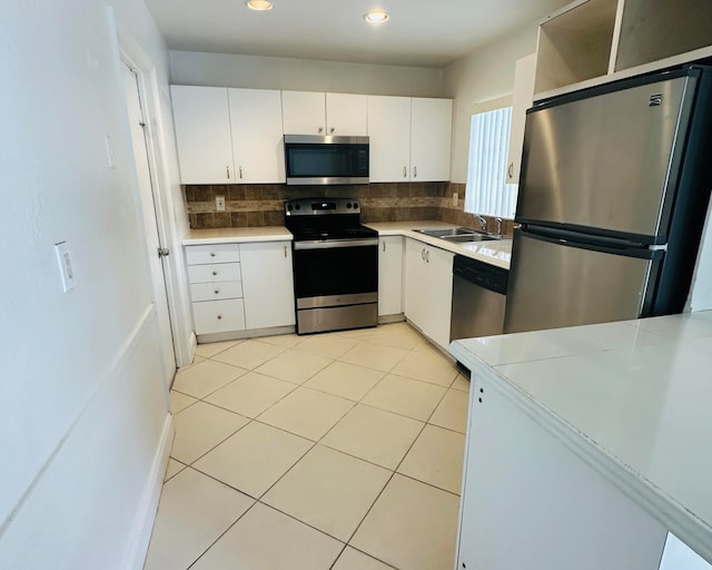 kitchen featuring decorative backsplash, appliances with stainless steel finishes, sink, white cabinets, and light tile patterned flooring