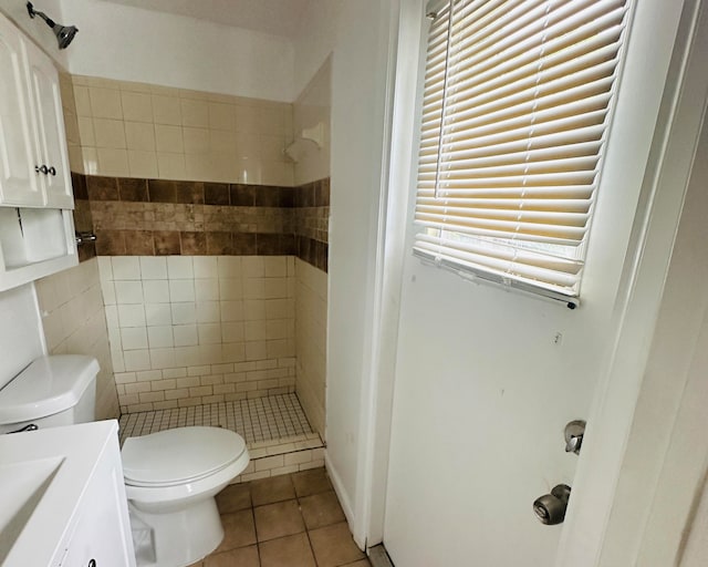 bathroom with tile patterned floors, vanity, toilet, and tiled shower