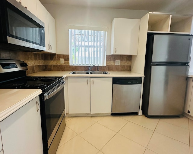 kitchen with white cabinets, sink, stainless steel appliances, and tasteful backsplash