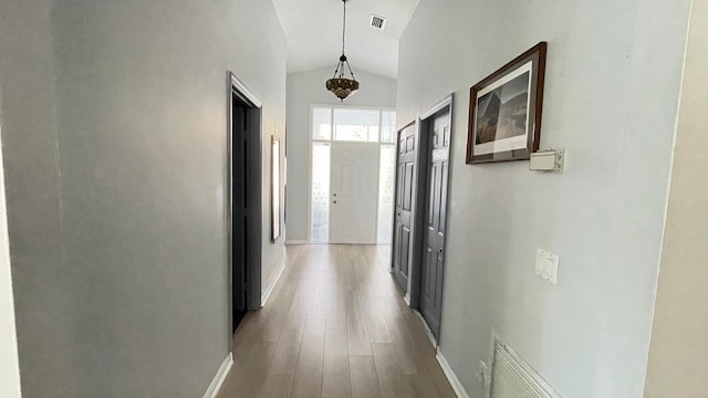 hall featuring light wood-type flooring and vaulted ceiling