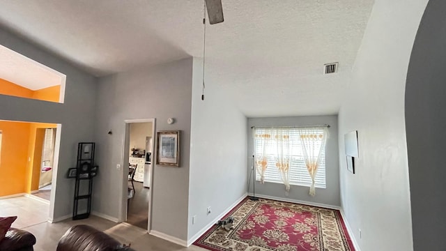 entrance foyer with ceiling fan, a textured ceiling, and high vaulted ceiling