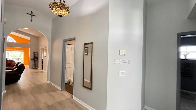 corridor with light hardwood / wood-style flooring and vaulted ceiling