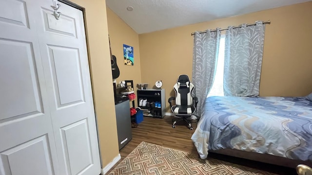 bedroom featuring a closet, multiple windows, wood-type flooring, and a textured ceiling