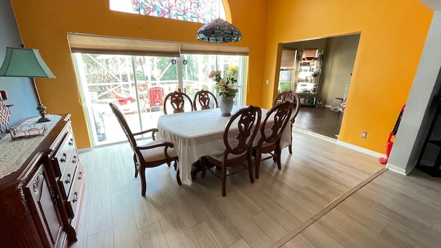 dining space featuring a towering ceiling and light wood-type flooring